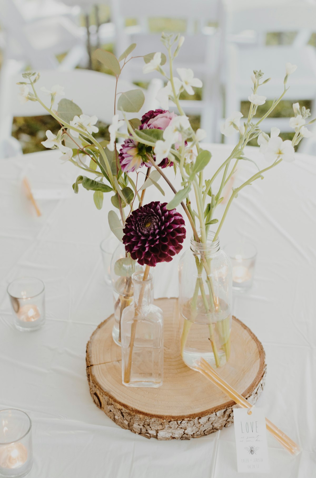 Deep burgundy dahlia and greenery in simple glass jars as a centerpiece at a rustic Bitterroot Valley Montana wedding