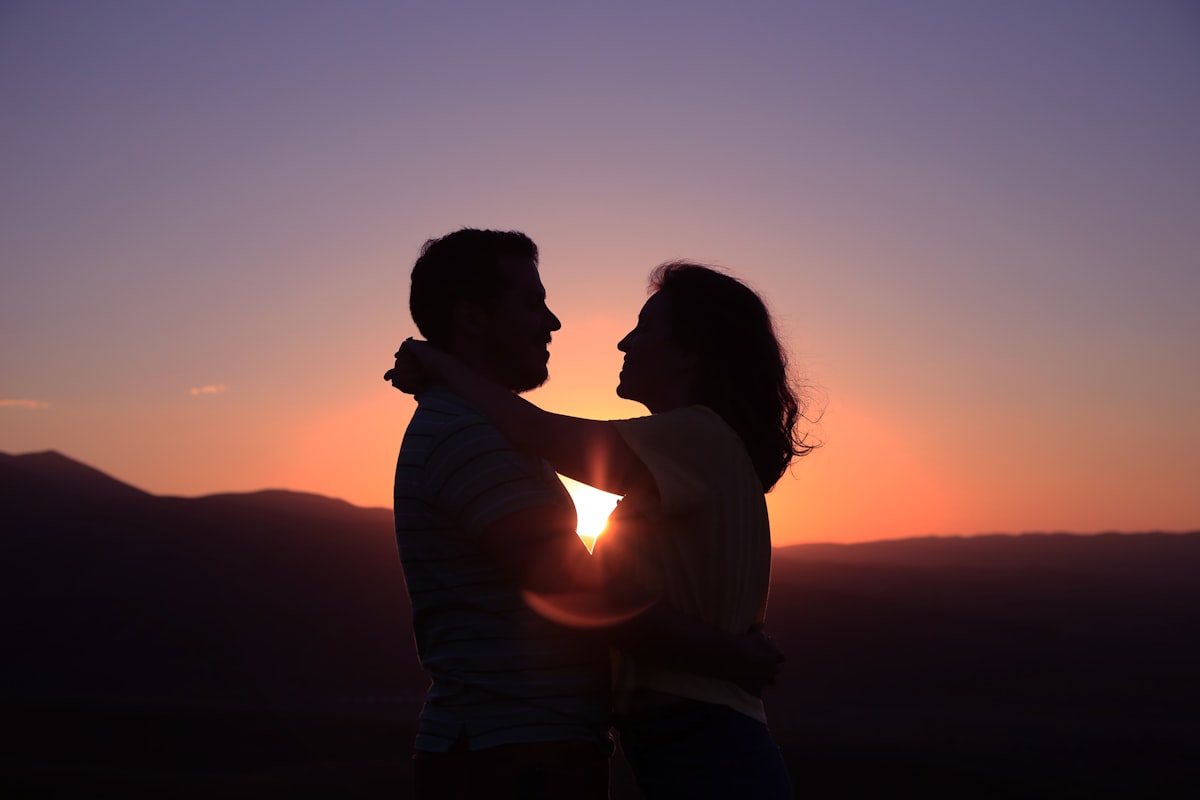 Wedding couple silhouetted against Montana mountain sunset at outdoor reception