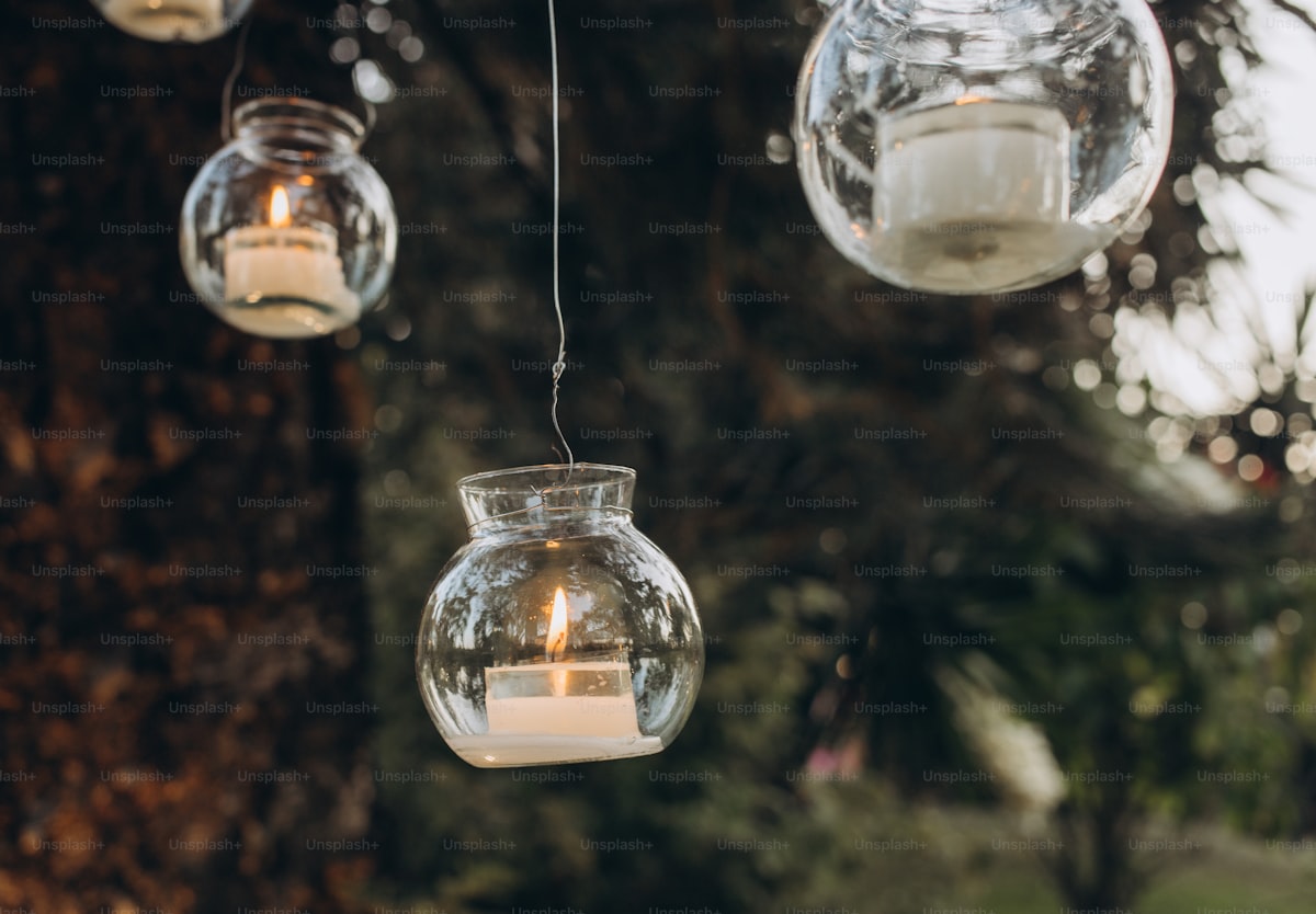 a group of hanging glass jars filled with candles