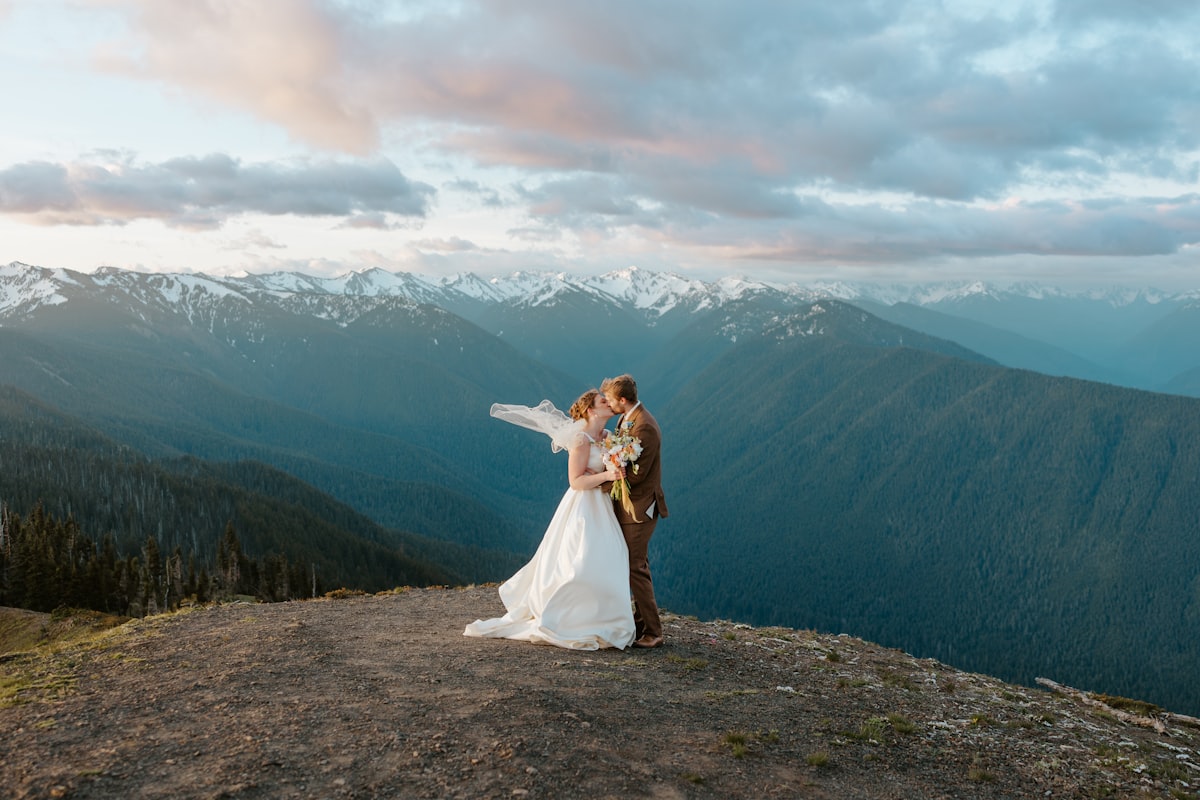 A bride and groom embrace on a mountain overlook.